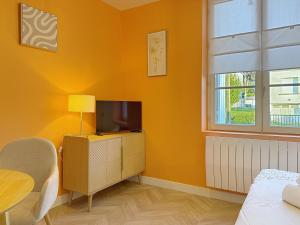 a yellow room with a television and a table at Teeny Ponta Plage in Royan