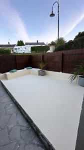 a white patio with a fence and some plants at Jolie Maison Proche Tous Commerces in Agneaux +1 photo