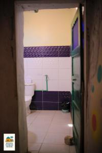 La salle de bains est pourvue de toilettes et de carrelage violet et blanc. dans l'établissement Heissa Nubian Hostel, à Aswân Reservoir Colony