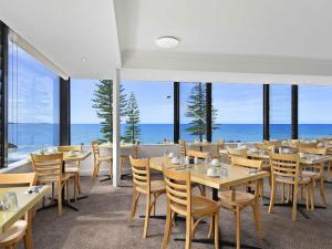 a restaurant with tables and chairs and a view of the ocean at ibis Styles Port Macquarie in Port Macquarie