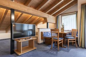 a living room with a large television and a table with chairs at Soliva Hotel & Apartments by MEIN SAMNAUN - MOUNTAIN HOMES in Samnaun
