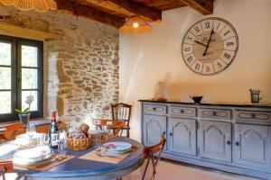 a dining room with a table and a clock on the wall at Maison de Dom - Au bord de la Dordogne in Brivezac +5 photos