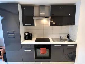 a kitchen with black cabinets and a sink at Le cocon du Florival- Guebwiller in Guebwiller
