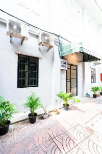 a white building with potted plants in front of it at X Rest Inn Yaowarat เรสอินน์ เยาวราช in Samphanthawong
