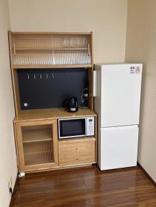 a small kitchen with a microwave and a refrigerator at 202 Room, a 6-minute walk from Tokyo Koiwa Station Direct connected to Shinjuku and Akihabara Stations Comfortable one-bedroom apartment with separate wet and dry areas in Tokyo