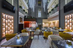 ein Restaurant mit Tischen und gelben Stühlen in der Unterkunft Hotel Allora in Budapest