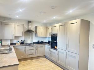 a kitchen with white cabinets and black appliances at 4 Bed House - Sleeps 7 - Pets - Parking - Wifi in Bushbury +9 photos
