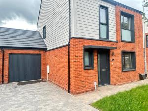 a red brick house with a black garage at 4 Bed House - Sleeps 7 - Pets - Parking - Wifi in Bushbury