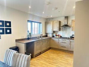 a kitchen with white cabinets and a wooden floor at 4 Bed House - Sleeps 7 - Pets - Parking - Wifi in Bushbury