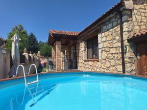 a swimming pool in front of a stone house at Casa Entre Hoces10-12paxJardín y barbacoa in Fuentemizarra