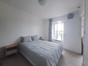 a white bedroom with a bed and a window at Le Champigny in Champigny-sur-Yonne