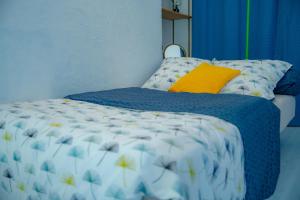 a bed with a blue and white comforter and a yellow pillow at CHAMBRES FAMILIALES ou PETITS GROUPES CAMPAGNE in Richarville +18 photos