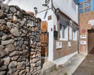 eine Steinmauer neben einem Gebäude mit einer Tür in der Unterkunft Mi Candela in Valleseco