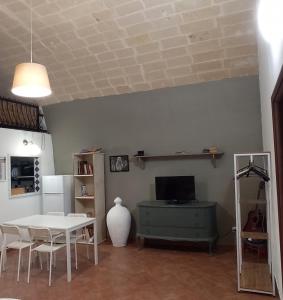 un soggiorno con tavolo bianco e TV di Palazzo Saraceno apartments-Antico Rifugio a Taranto