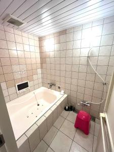 a bathroom with a tub and a pink stool at Hotel An no Ie - Vacation STAY 80310v in Ikaho