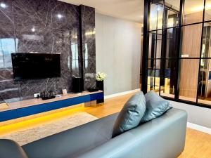 a living room with a couch and a tv at The Prestige Living Bangkok at Sathorn-Chan in Bangkok