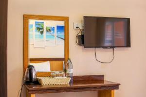 a flat screen tv hanging on a wall next to a mirror at Ari Stay Thoddoo in Thoddoo