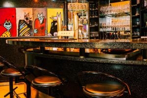 a bar with three stools in a room with paintings at Kulturhotel Hessenland Kassel Innenstadt by stay awesome in Kassel +32 photos
