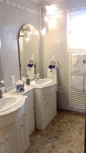 ein weißes Badezimmer mit zwei Waschbecken und einem Spiegel in der Unterkunft Les Hortensias Du Monastère in Saint-Aubin-de-Médoc + 9 Fotos