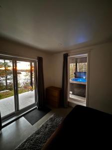 a bedroom with a bed and a large window at Chalet Cottage Le Bellevarde Hot tub Lake view in Saint-Aimé-Du-Lac-des-Îles