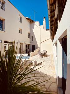 a courtyard with white buildings and a table and chairs at Grande maison de ville MALO LEONE 250m2 pour 15 personnes proche du Puy du Fou in Mauléon