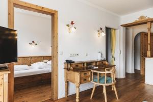 トゥルラッハー・ヘーエにあるSeehotel Jägerwirtの机とベッドと鏡のある寝室 +68枚の写真
