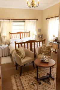 FraserburgにあるOu Klipskuur Self-Catering Accommodationのベッドとテーブルと椅子のある寝室