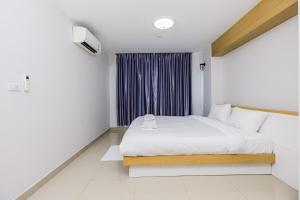 a white bedroom with a bed and a window at Fin Banchang in Ban Nong Chaeng