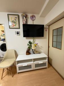 sala de estar con armario blanco y TV de pantalla plana en Uhome Akazu hostel, en Tokorozawa