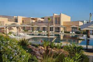 ein Resort mit einem Swimmingpool mit Stühlen und Sonnenschirmen in der Unterkunft Radisson Residences Taghazout Bay in Agadir