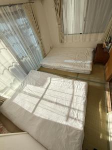 Dos camas en una habitación con ventana. en Uhome Akazu hostel, en Tokorozawa