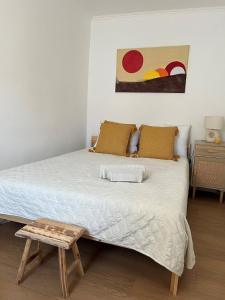 a bedroom with a large bed with a wooden stool at Casa da Mó - Conforto, Charme e Piscina privada no Coração do Alentejo in Beringel