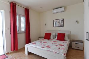 - une chambre avec un lit et des rideaux rouges dans l'établissement Apartment natalia, à Podgora