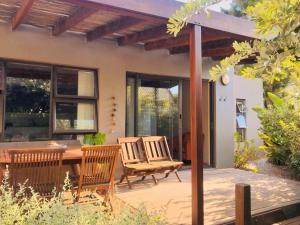 a patio with a wooden table and chairs and a house at Point Garden Cottage in Elands Bay