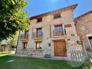 an old stone building with a wooden door and windows at Hotel Rural Villa Liquidámbar in Torrecilla en Cameros