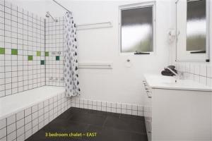 a white bathroom with a tub and a sink at Sea Breeze East Chalet Yallingup in Yallingup