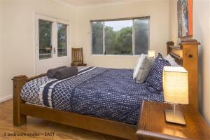 a bedroom with a bed and a table and windows at Sea Breeze East Chalet Yallingup in Yallingup