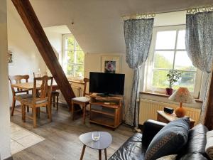 ein Wohnzimmer mit Sofa und Fernseher in der Unterkunft Lüttje Paradies in Ruhwarden