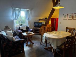 ein Wohnzimmer mit Tisch und Stühlen und einem Fernseher in der Unterkunft Lüttje Paradies in Ruhwarden