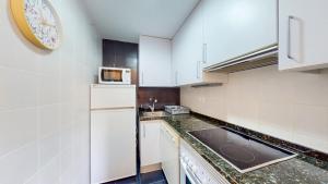 a kitchen with white appliances and a clock on the wall at Apartamento en Alcala de la Selva by Family Homes in Alcalá de la Selva