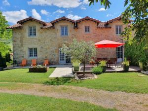 une grande maison en pierre avec un parapluie rouge dans l'établissement Gîte de Ségonac, à Saint-Georges-de-Luzençon