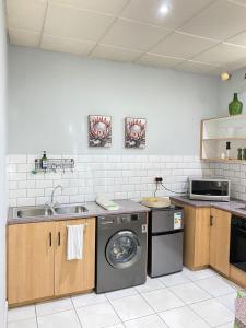 a kitchen with a sink and a washing machine at The Protea & Vine in Paarl