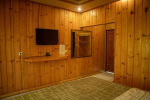 a bedroom with wooden walls with a television and a bed at Cemara Indah Hotel in Bromo