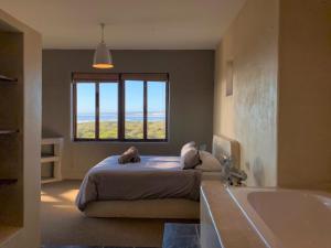 a bedroom with a bed and a tub and a window at Elands One in Elands Bay
