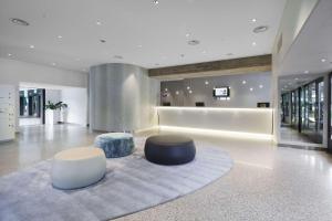 a lobby with two ottomans and two stools at NH Milano Congress Centre in Assago