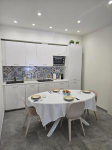 a kitchen with a white table with chairs and a white table cloth at Casetta Di Nonno Paolo in Contrada Mastrissa