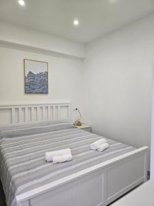 a white bedroom with a large bed with two towels at Casetta Di Nonno Paolo in Contrada Mastrissa