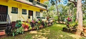 a yellow house with flowers in front of it at KAMAT GUEST HOUSE in Sinquerim