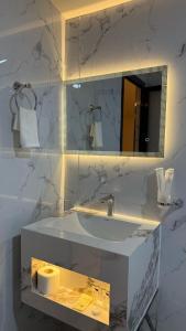 a white bathroom with a sink and a mirror at Atana bidiyah private camp in Al Raka