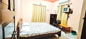 a small bedroom with a bed and a television at KAMAT GUEST HOUSE in Sinquerim